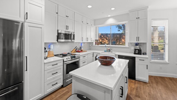 A modern kitchen with white cabinetry, stainless steel appliances, and a large island. - Family Friendly Hurst Home with Salwater Poo,l Fireplace, and Spacious Layout (Hurst)