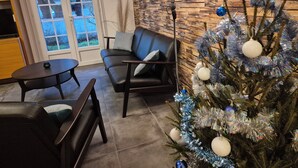 A cozy living room with a leather sofa, a small round table, and a Christmas tree decorated with silver and blue ornaments. - Cosy villa, 6 pers, 800m from the beach, large garden (Fouras)
