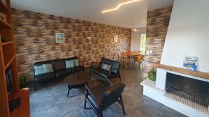 A modern living room with a stone wall, a fireplace, a dining area, and a sofa set. - Cosy villa, 6 pers, 800m from the beach, large garden (Fouras)