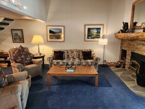 Ein Wohnzimmer mit einer Couch, Sesseln, einem Couchtisch und einem Kamin.