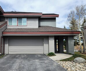 Ein zweistöckiges Haus mit Garage, einem Kiesweg und einer Auffahrt.