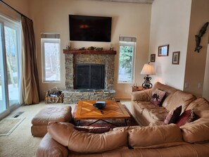 A living room with a stone fireplace, leather sofa, and a flat-screen TV. - Snowcreek Resort Vacation Rental 511 (Mammoth Lakes)