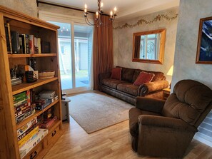 Ein Wohnzimmer mit einer Holzhülle, einem braunen Sofa, einem braunen Sessel und einem Fenster mit Vorhängen.