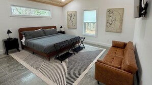 Ein modernes Schlafzimmer mit einem großen Bett, einem Deckenventilator und Kunstwerken an den Wänden.
