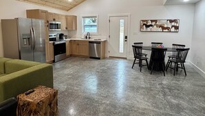 Eine moderne Küche mit Holzschränken, Edelstahlgeräten und einem Essbereich mit Tisch und Stühlen.