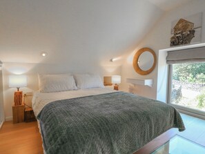 Un dormitorio con cama, dos lámparas de noche, un espejo circular y una ventana con vistas.