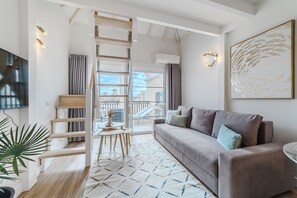 Una sala de estar moderna con sofá, televisión, una escalera y vistas al exterior.