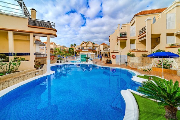 Una piscina rodeada de edificios con balcones y un cielo despejado.