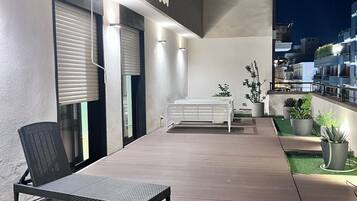 An outdoor patio area with a lounge chair, a small table, and potted plants.