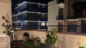 An outdoor seating area with a pool, surrounded by potted plants and a modern building in the background. - Best Stay-Apartments in Andrea da Bari 5 (Bari)