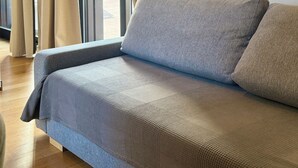 A modern room with a sofa, curtains, a phone, and a framed picture on the wall. - Best Stay-Apartments in Andrea da Bari 5 (Bari)