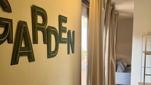 A hallway with a sign reading "GARDEN" on the wall, leading to a room with a bed and a wooden floor. - Best Stay-Apartments in Andrea da Bari 5 (Bari)