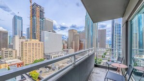 Een balkon met uitzicht op een stadsgezicht, inclusief wolkenkrabbers en een bouwkraan.