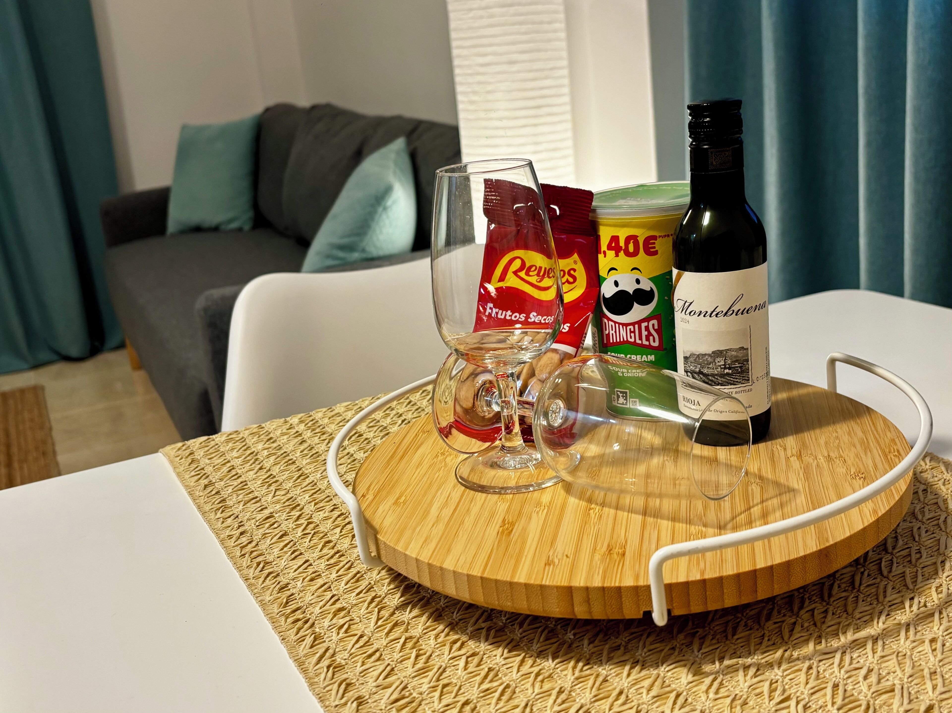 Een tafel met een fles wijn, een glas en hapjes.