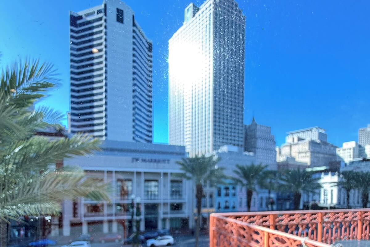 A cityscape with tall buildings, palm trees, and a bridge with ornate railings.