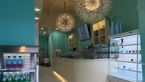 A modern cafe with teal walls, a central counter, and a refrigerated display case filled with beverages. - Jimmys on Canal St  (New Orleans)