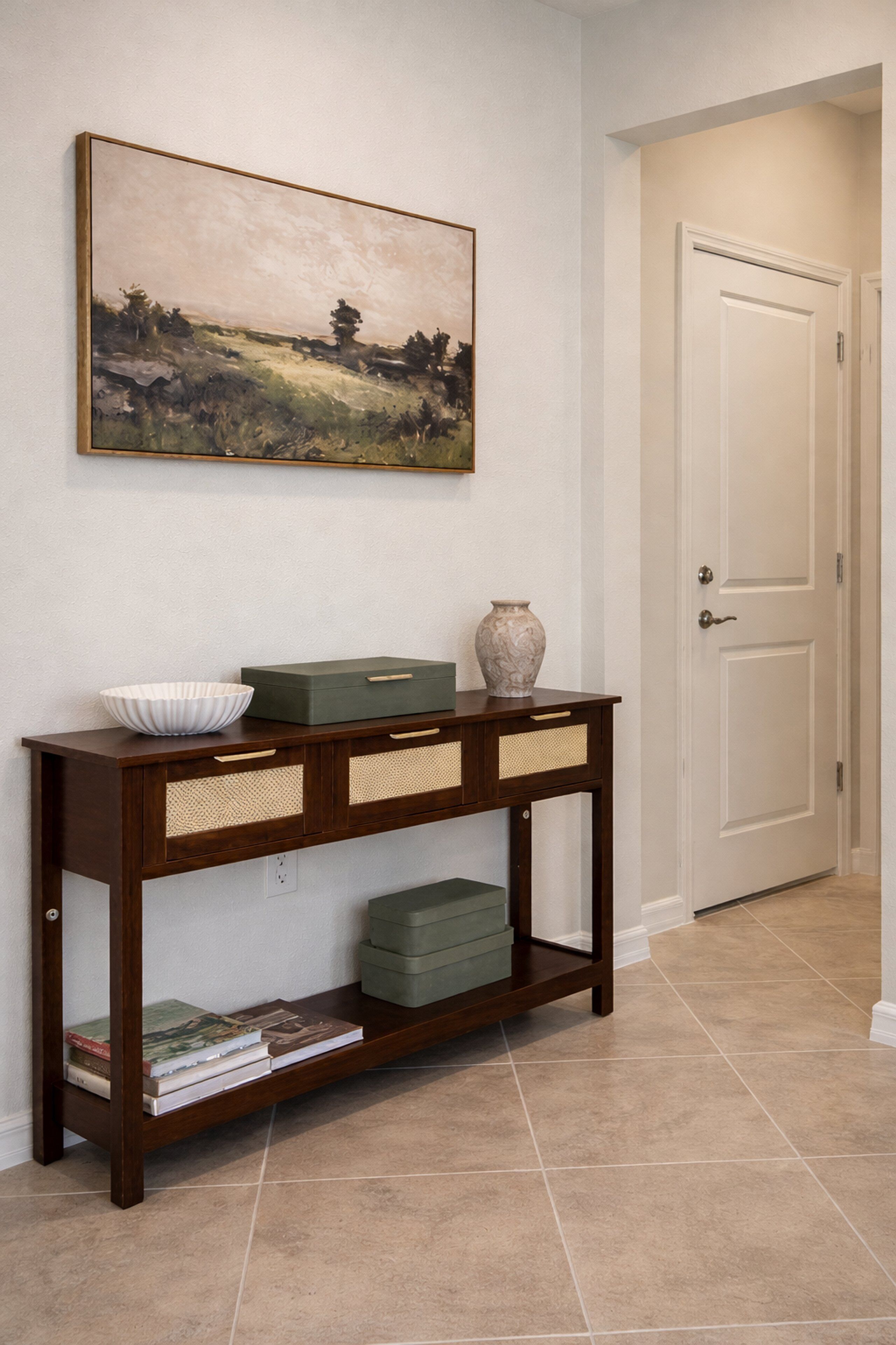A wooden console table with a bowl, a vase, and books.