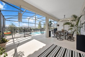A spacious indoor area with a glass ceiling, a pool, and a dining area with chairs and a table. - Solterra 6BR Lakeview + Pool & Game Room (Davenport)