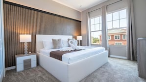 Ett modernt hotellrum med en stor säng, två sängbord med lampor, utsikt över en byggnad genom fönstret och en väggpanel i trä.