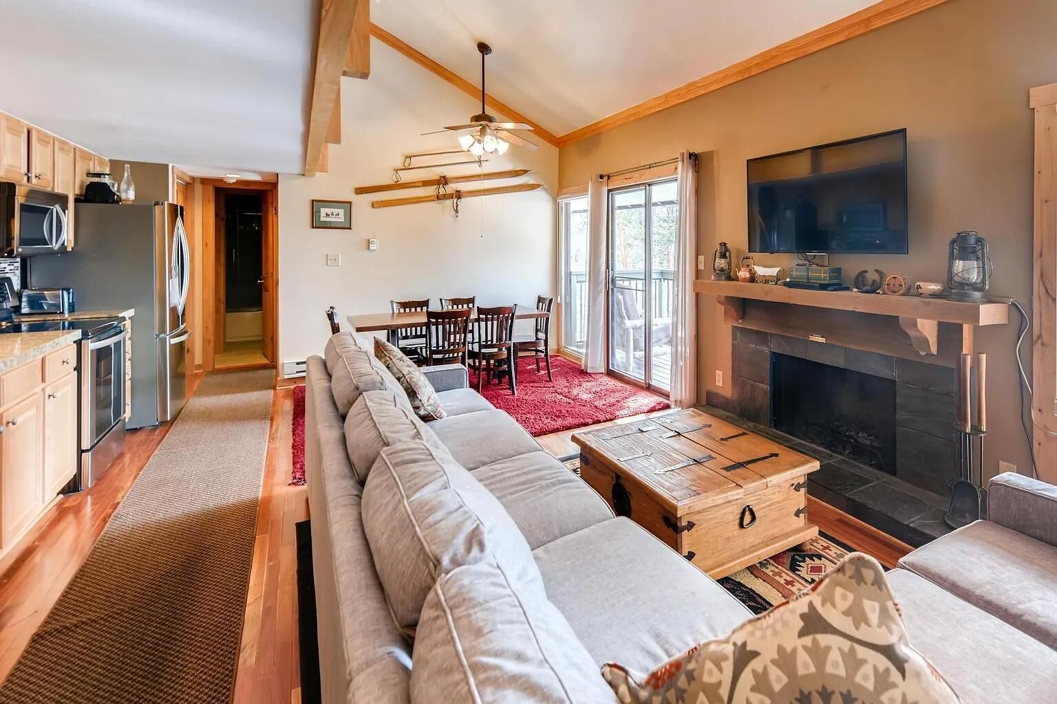 A spacious living room with a long sofa, a fireplace, and a dining area with wooden furniture.