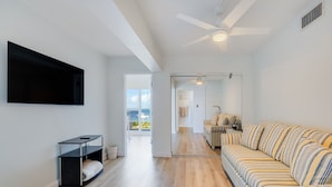 Een moderne woonkamer met een grote bank, een flatscreen televisie en een houten vloer.