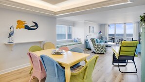 Een moderne woonkamer met een eethoek, grote ramen en uitzicht op zee.