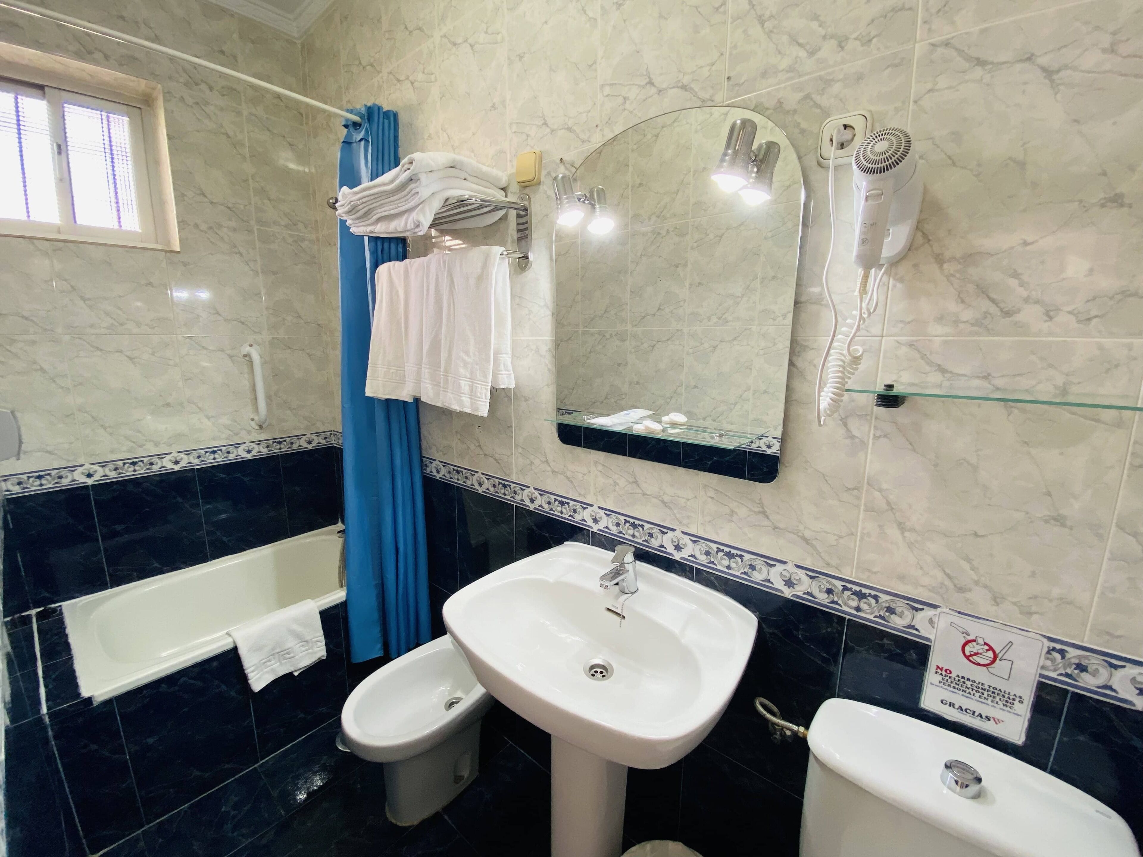 Un baño con bañera, bidé, lavamanos y espejo.