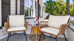 Ein Korbsitz-Set mit Tisch auf einer Veranda mit Blick auf ein Haus und Bäume.