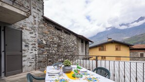 Ein Essbereich im Freien mit Tisch für zwei Personen, einer Steinsäule und Blick auf die Berge.
