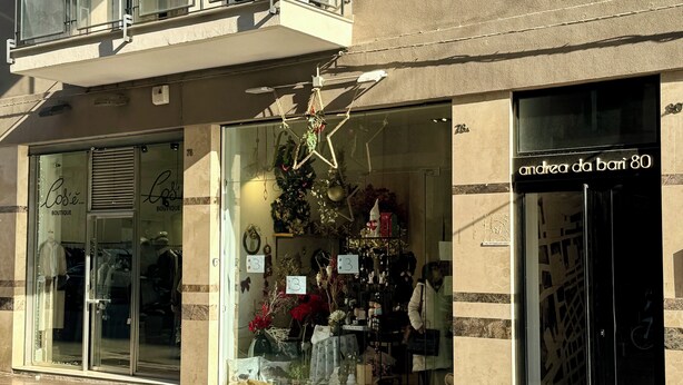 Una tienda boutique con escaparates de vidrio y un balcón.