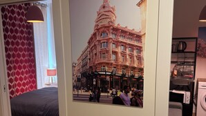 Una habitación con cama, escritorio, silla, lavadora y un cartel de un edificio.