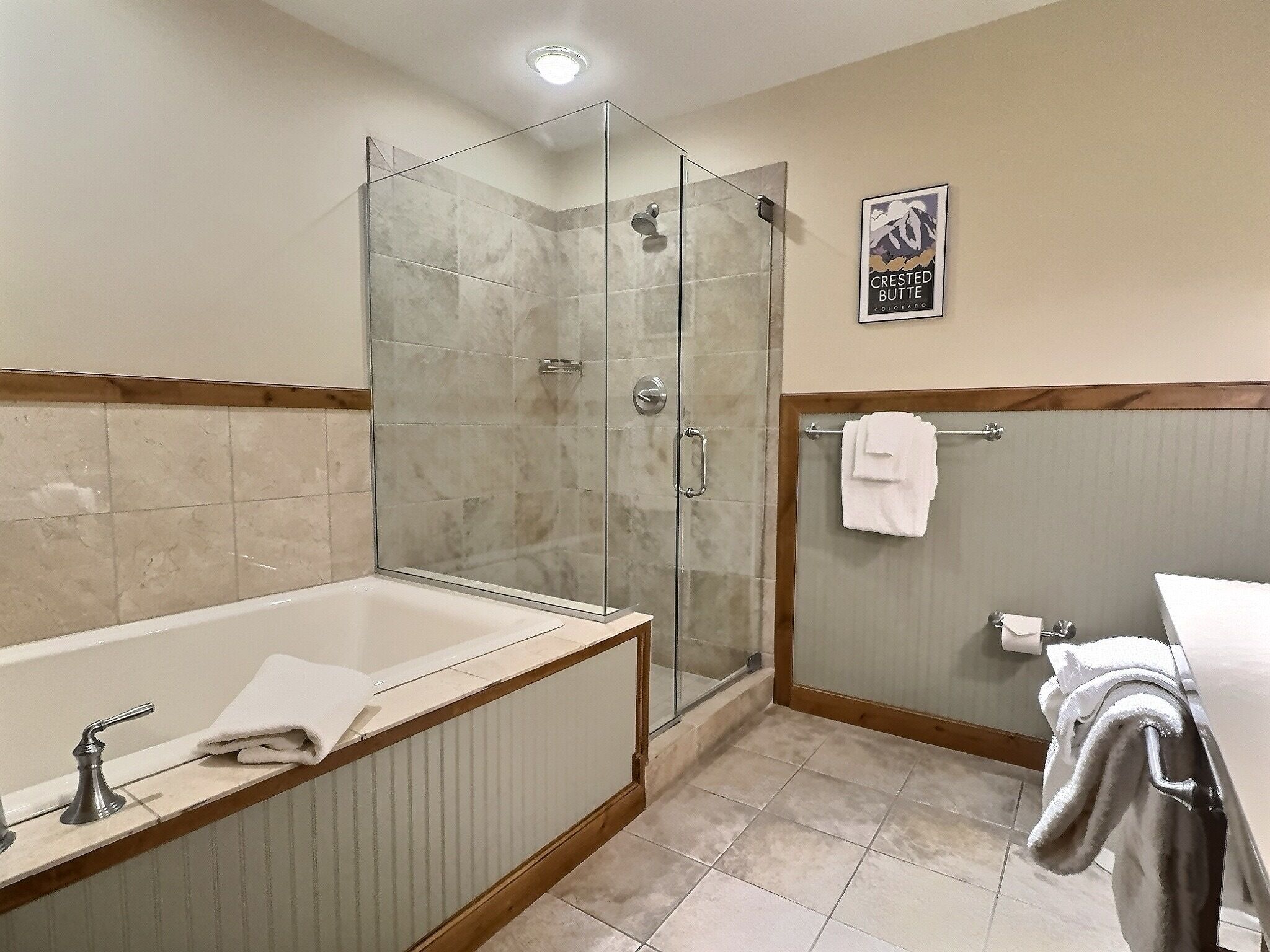 A modern bathroom with a glass-enclosed shower, a freestanding bathtub, and a toilet with a towel rack.