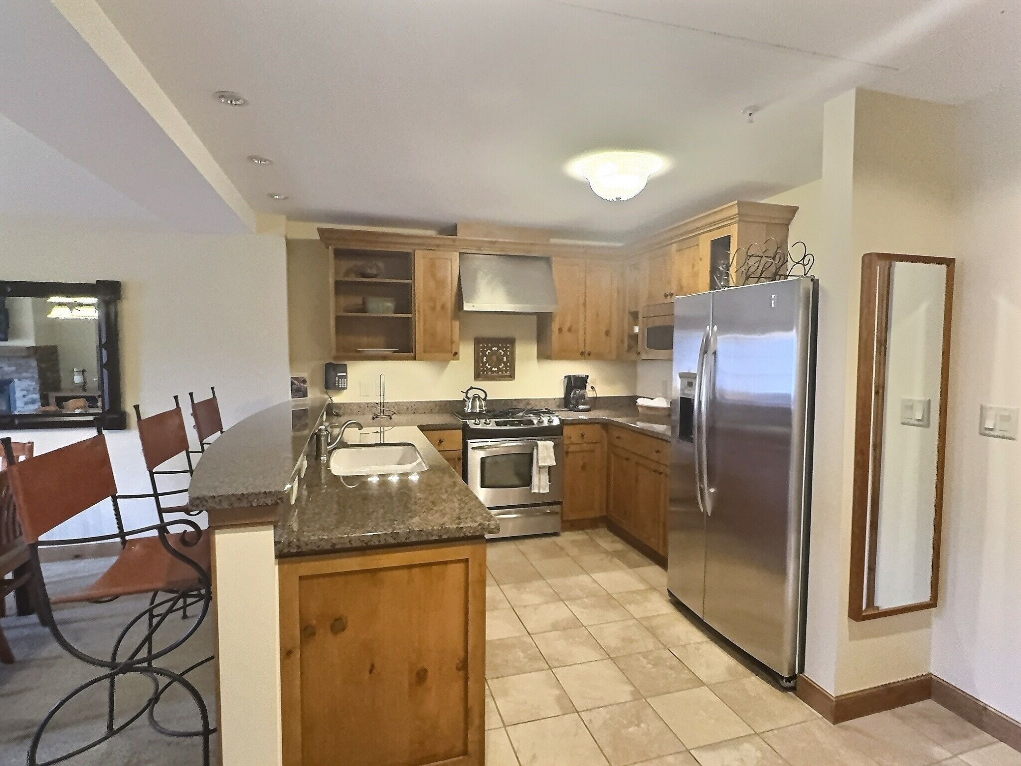A kitchen with wooden cabinets, a stainless steel refrigerator, a stove, and a sink.
