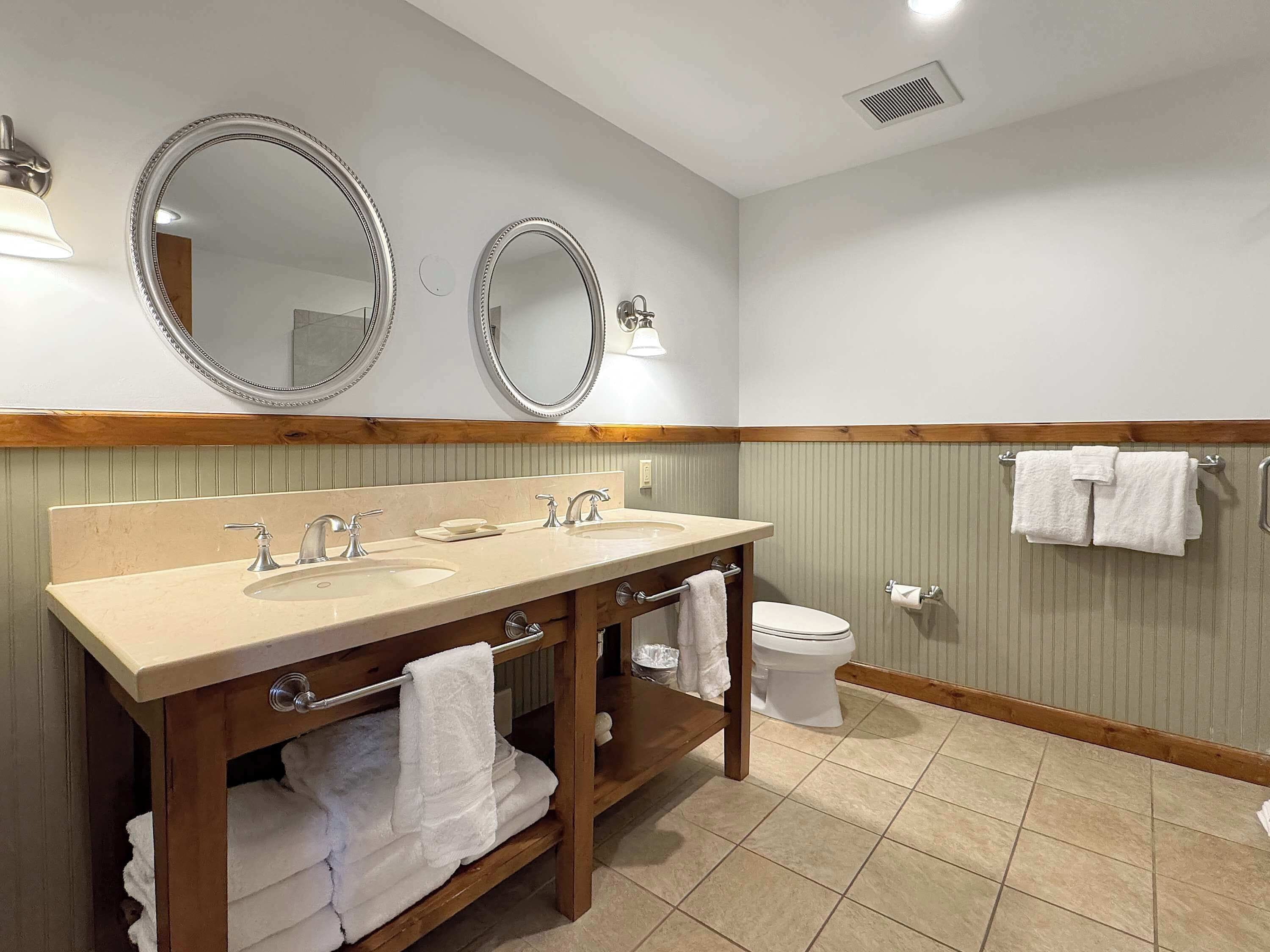 A bathroom with two sinks, two mirrors, a toilet, and towels.