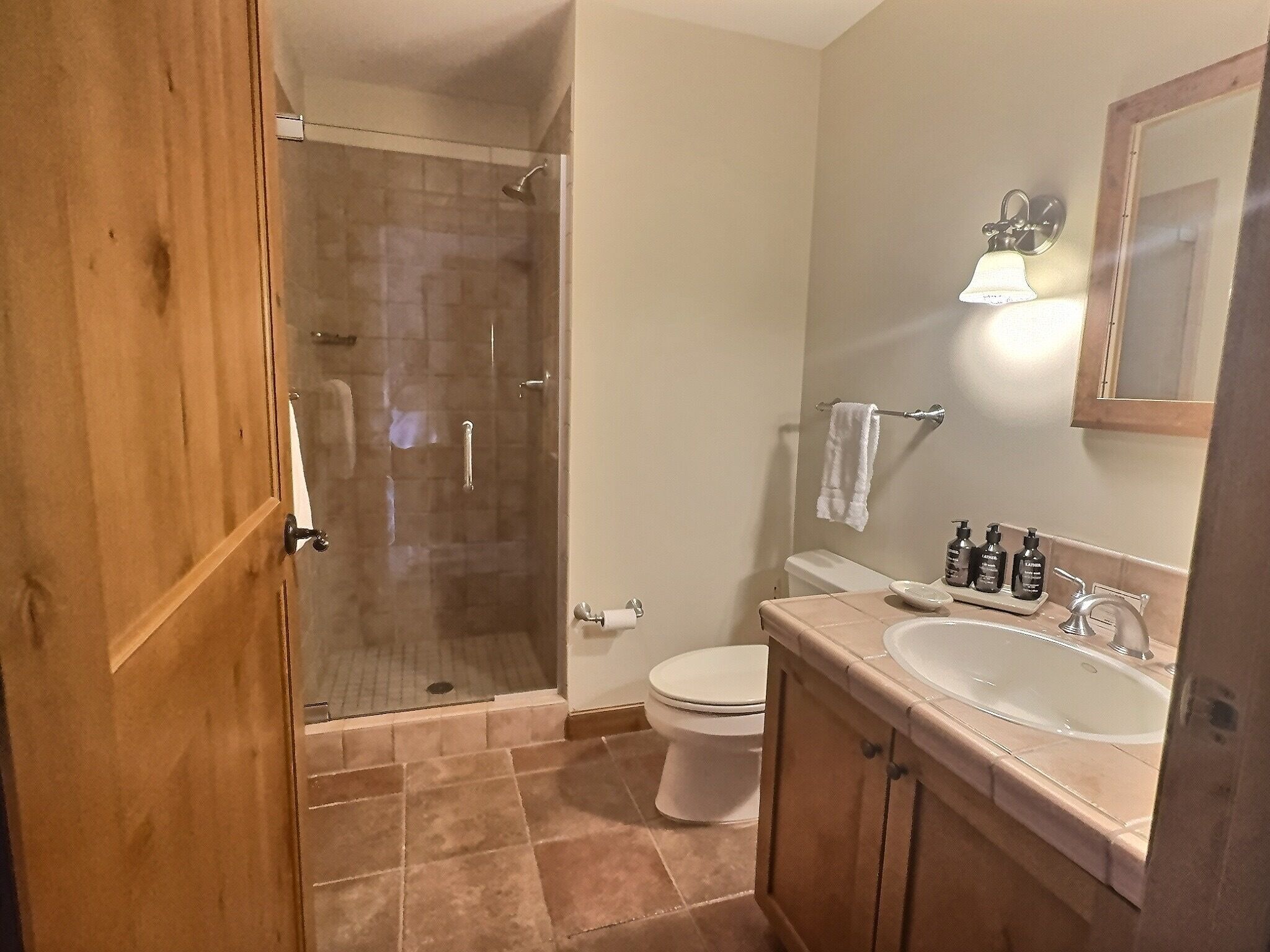 A bathroom with a shower, toilet, sink, and vanity.