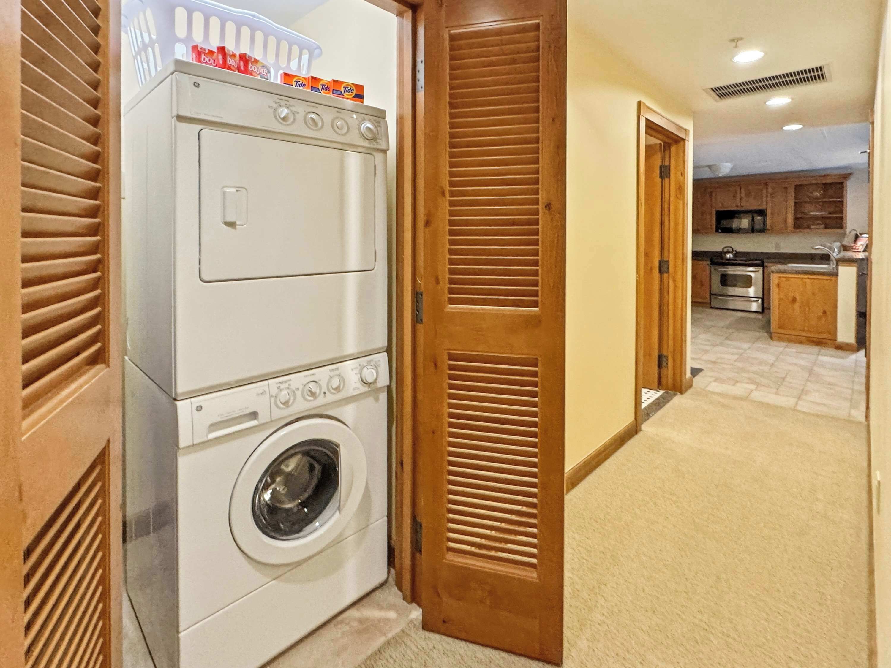 A laundry room with stacked laundry detergent boxes, a washing machine, and a dryer.