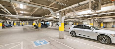 An underground parking garage with multiple levels, concrete pillars, and marked parking spaces.