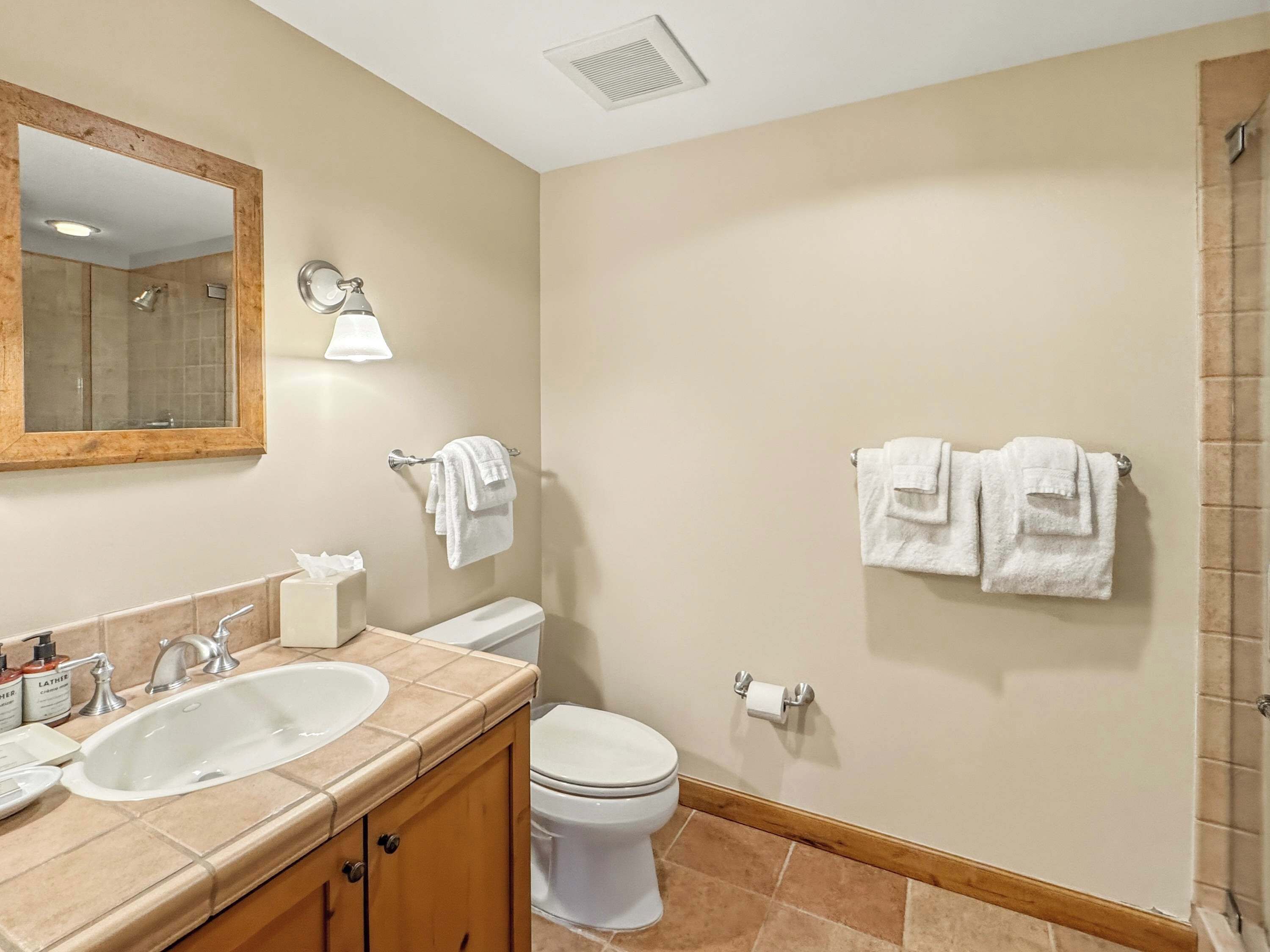 A bathroom with a double sink, toilet, and two towels hanging on the wall.
