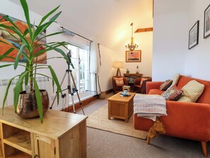A cozy living room with a wooden coffee table, a red sofa, and a large potted plant. - Baywatch (Lynton)