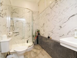 Un baño con ducha acristalada, inodoro y lavabo.