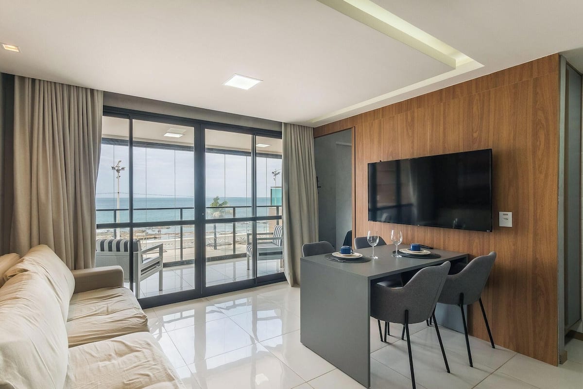 Une chambre d’hôtel moderne dotée d’un balcon, d’un canapé, d’un coin repas et d’une télévision.