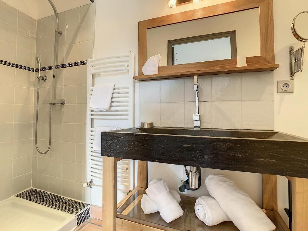 Une salle de bain moderne équipée d’une douche, d’un meuble-lavabo avec un miroir et d’un porte-serviettes.
