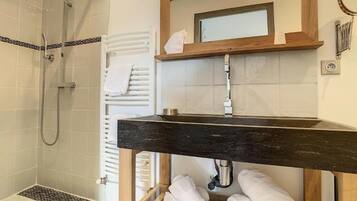 Une salle de bain moderne équipée d’une douche, d’un meuble-lavabo avec un miroir et d’un porte-serviettes.