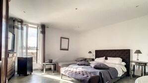 Un dormitorio con una cama grande, mesitas de noche, un aparador y una ventana con cortinas.