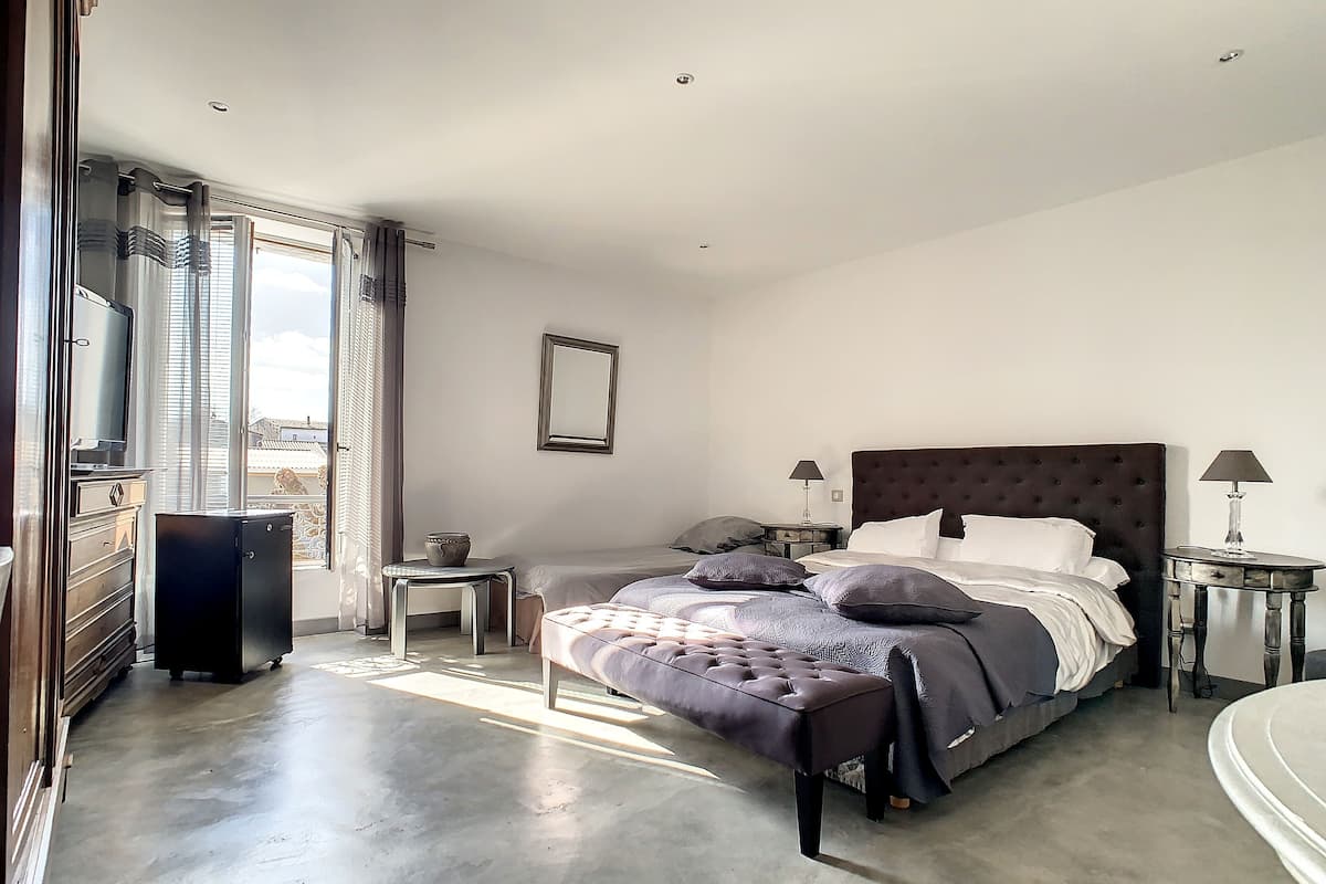 A bedroom with a large bed, bedside tables, a dresser, and a window with curtains.