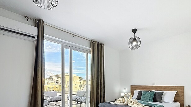 A modern bedroom with a large bed, a desk, and a view of the city through the window. - Luxury Penthouse Holiday Stay Property in Gzira (Il-Gżira)