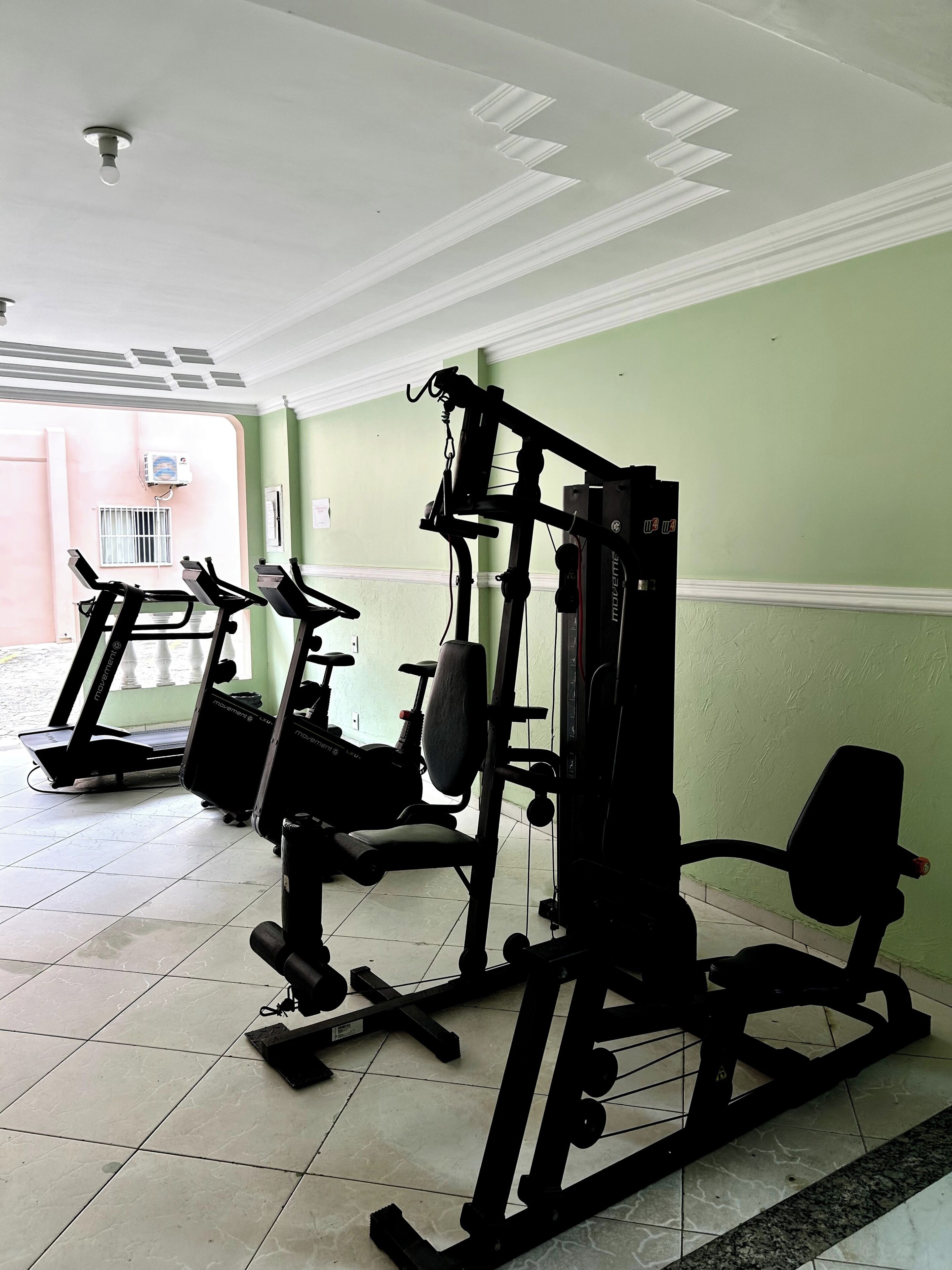 A gym with treadmills, a weight machine, and a wall-mounted air conditioning unit.