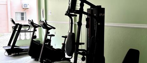 A gym with treadmills, a weight machine, and a wall-mounted air conditioning unit.