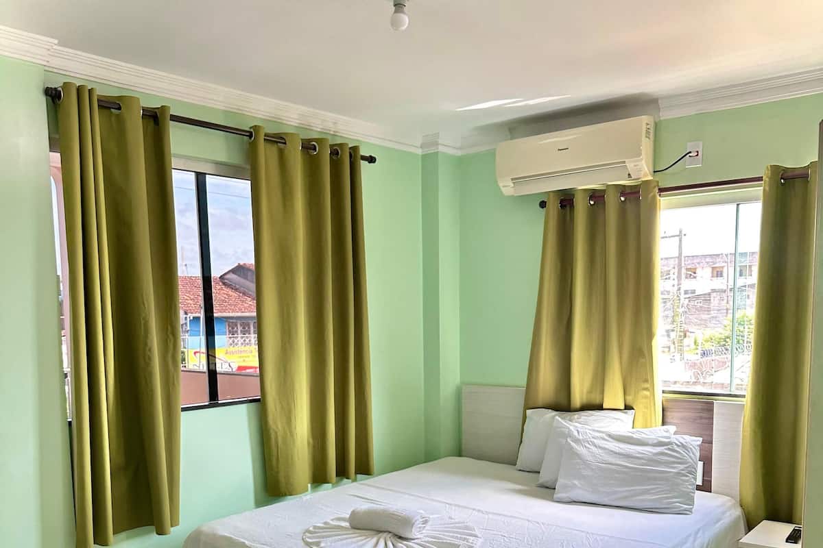 Habitación de hotel con cama, escritorio, silla y ventana con cortinas.