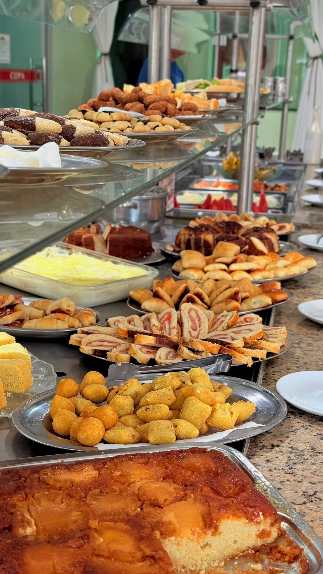 A buffet with various food items including pastries, sandwiches, and a cake.
